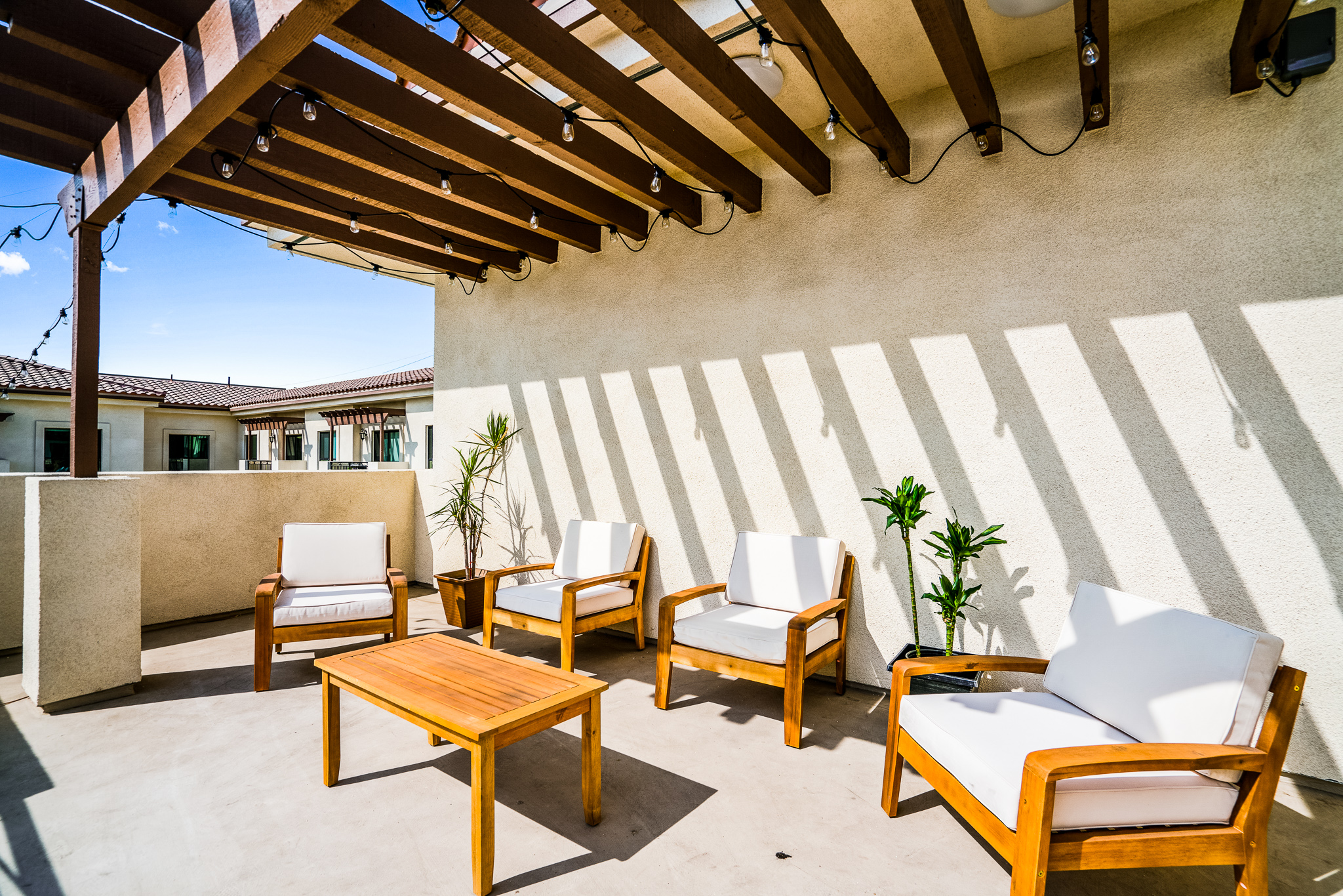 Cushion-covered wood furniture with plants on the elevated community patio at Gladstone Senior Villas.